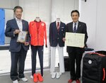 東京オリンピックの試合用ユニホームなどを向日市に寄贈した田村さん（右）＝向日市森本町・市民体育館