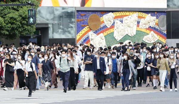 東京・渋谷のスクランブル交差点でマスクを着けて横断する人たち＝２０日午後