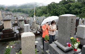 雨が降る中、墓前で手を合わせる親子連れ（１３日午前１０時、京都市東山区・大谷本廟）