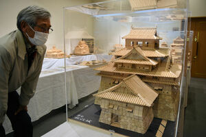 つまようじを組み合わせて城や寺の模型を作る佐藤さん。「黙々と作業すると夢中になる」という＝竜王町綾戸・町図書館