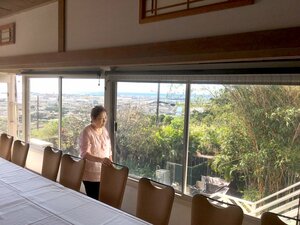 料亭「夏の家」の２階から外を見る藤原さん。大きな窓からは真珠湾が一望できる（米ハワイ・ホノルル、２０１９年１月撮影）