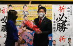 支援者から花束を受け取り笑顔を見せる山田さん（右）＝１８日午後１０時３７分、島本町水無瀬２丁目