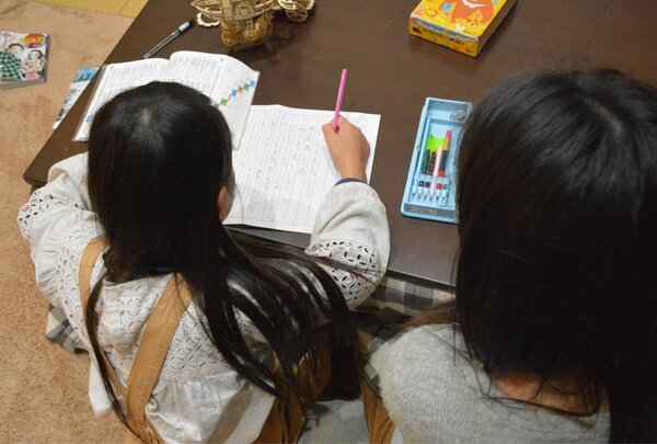学級閉鎖中、学校から配られた学習プリントに取り組む小学生。分からない点などがあれば母親（右）が横に来て教える＝京都市北区