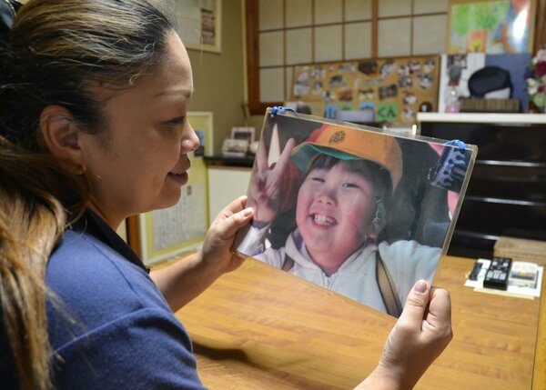 笑顔でピースサインをする山名空君の写真を見つめる母親の三千代さん（８日、京都府京丹波町実勢）
