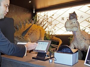 「変なホテル」で、恐竜型ロボットの接客によるチェックインを実演する担当者＝東京都江戸川区
