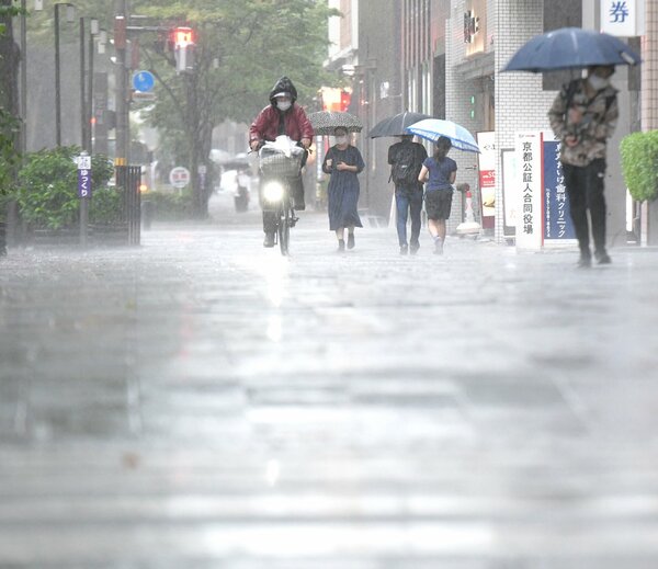 強い雨が降る中、傘をさして歩く人たち（2021年8月17日午後3時16分、京都市中京区烏丸御池交差点付近）