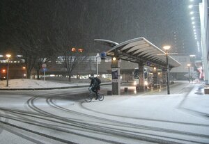 雪が降り始めたＪＲ東舞鶴駅前。自転車に乗った人が、雪化粧した路面に気をつけながら走っていた（１月１３日午後７時５６分、京都府舞鶴市浜町）