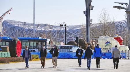 北京冬季五輪メインメディアセンター周辺のバブル内を散歩する関係者。奥は開閉会式が行われる国家体育場＝２５日、北京（共同）