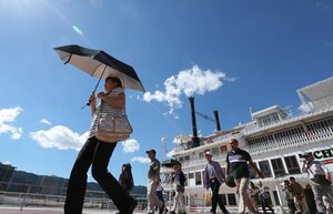 厳しい日差しの中、日傘やタオルを手に琵琶湖の遊覧船から降りる人たち（２３日午後２時５０分、大津市浜大津５丁目・大津港）