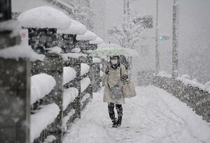強い雪が吹き付ける中、傘を差して橋を渡る人たち（２１日午前９時４０分、京都市北区・北大路橋）