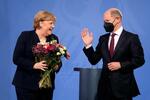 ８日、ベルリンで、ショルツ新首相（右）から花束を受け取るメルケル前首相（ＡＰ＝共同）