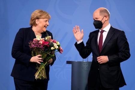 ８日、ベルリンで、ショルツ新首相（右）から花束を受け取るメルケル前首相（ＡＰ＝共同）