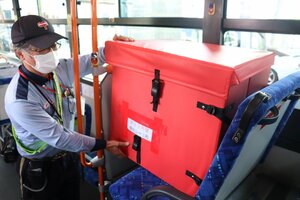 郵便物が入った専用ボックスをバスの客席部分に積む福知山郵便局の職員（福知山市天田）